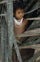 Young Waorani girl outside hut.