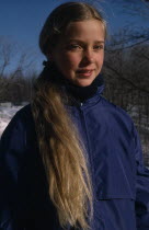 Portrait of young girl with long blonde hair outdoors  dressed for cold weather.