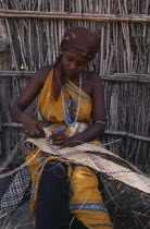 Woman making woven mat.