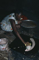 Dinka tribeswoman making flatbread inside hut.Africa African North Africa Sudanese