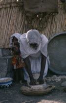 Woman making bread with young child beside her.Africa African Children Female Women Girl Lady Immature Kids North Africa Sudanese