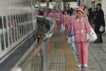 A cleaning crew of middle aged women in uniform wait to board a bullet train  shinkansen   to clean it.Asia Asian Japanese Nihon Nippon Cleansing Female Woman Girl Lady Washing