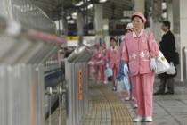 A cleaning crew of middle aged women in uniform wait to board a bullet train  shinkansen   to clean it.Asia Asian Japanese Nihon Nippon Cleansing Female Woman Girl Lady Washing