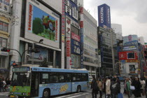 The main intersection outside Shinjuku Station  crowds crossing the road  a blue bus  advertising on buildings.Asia Asian Japanese Nihon Nippon
