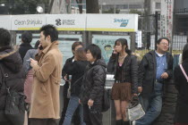 Outside Shinjuku Station  smokers light up at a smoking station  including a young woman in a miniskirt.Asia Asian Japanese Nihon Nippon Female Women Girl Lady Immature