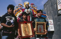Pilgrims carrying icons and standing in front of statue of the Virgin Mary decorated with flowers at the Basilica de Guadeloupe for Day of Our Lady of Guadeloupe festival.