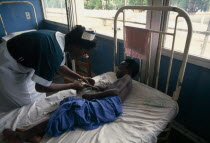 Bedridden child being attended by nurse in children s ward of Korle-Bu teaching hospital.