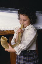 Young Jewish girl blowing the Shofar.