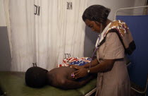 Female doctor examining boy in Kawempe clinic.