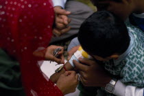 Woman tying thread on arm of boy during the Sacred Thread ceremony. The Hindu male rite of passage ceremonyAsian European Great Britain Northern Europe Religion Religion Religious Hinduism Hindus UK...