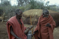 Two old Masai men wearing traditional red clothing in their Boma.Village African Eastern Africa Kenyan