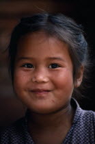 Head and shoulders portrait of smiling young Gurkha girl.