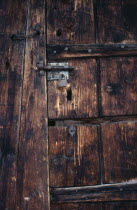 Detail of wooden door of old French farmhouse with bolt  padlock and chain and original keyhole.