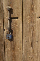 Detail of wooden door with metal handle and padlock.