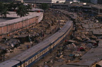 Train passing through overcrowded slum housing lining the railway track.