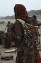 Mother carrying baby on her back in leather sling decorated with beads and cowrie shells.African Babies Eastern Africa Ethiopian Kids Mum