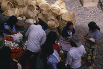 Looking down on customers at fruit and vegetable stall in market with piled baskets behind.American Hispanic Latin America Latino Mexican