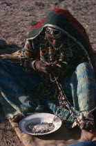 Kalbelia gypsy woman in traditional dress stringing beads.