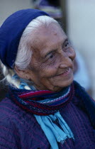 Matriarchal society.  Head and shoulders portrait of elderly woman with white hair wearing purple dress and blue headscarf.American Female Women Girl Lady Hispanic Latin America Latino Mexican Old Se...