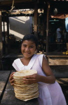 Smiling young girl selling tortillas at market.American Happy Hispanic Immature Kids Latin America Latino Mexican One individual Solo Lone Solitary 1 Contented Single unitary Young Unripe Unripened G...