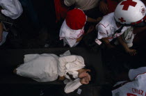 Woman being carried through crowd on stretcher by emergency services during Festival of Our Lady of GuadaloupeAmerican Female Women Girl Lady Hispanic Latin America Latino Mexican Religion Female Wom...