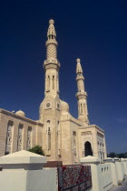 Jumeirah Mosque.  Angled view of exterior with pair of minarets and domed rooftop decorated with hexagonal pattern.  Carpet lying over white wall in foreground.Dubayy Religion Religious United Arab E...