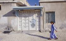 Young girl passing building with carved and decorated doorway.  Sheikh Zayed Road behind.Dubayy Immature Kids One individual Solo Lone Solitary United Arab Emirates 1 Al-Imarat Al-Arabiyyah Al-Muttah...