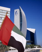 National Bank of Dubai seen from dhow on Dubai creek with UAE flag in the foreground.Dubayy United Arab Emirates Al-Imarat Al-Arabiyyah Al-Muttahidah Arabic Emiriti Middle East