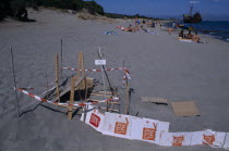 Sea Turtle protection consisting of wood and cardboard forming a cordon around an area on sandy beach near sunbathersEuropean Beaches Ecology Ellada Entorno Environmental Environnement Greek Green Is...