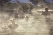 People in the outdoor hot pool of the spa resort  with steam rising in the cold air.