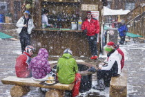 Skiers at outdoor bar in the snow.