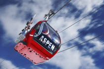 View of cable car ski lift against blue sky with clouds.