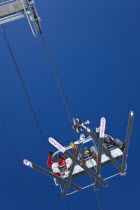 View of cable ski lift chair against blue sky with clouds.