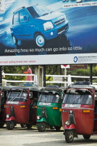 Tuk Tuks parked underneath advertising billboard for Suzuki WagonR.