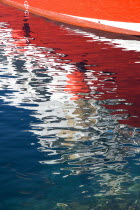 Reflection of red hull of boat in rippled waters of the harbour Puerto del Carmen.Espainia Espana Espanha Espanya European Hispanic Southern Europe Spanish Reflexion