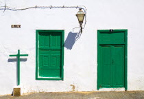 Teguise  former capital of the island.  Detail of house facade with typical white painted walls and green door and window shutters  cross and lantern cast shadows.Espainia Espana Espanha Espanya Euro...