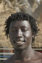 Tanji coast.  Head and shoulders portrait of smiling young African man with short dreadlocks. TanjehTanjihfaceAfricancharacteristicsexpressionsmileemotionracemoodethnichairGambian Happy I...