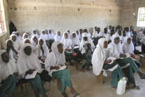 Tanji Village.  Muslim students attending a class at the Ousman Bun Afan Islamic school.  Girls sitting seperately from boys  to one side in foreground wearing uniform of white headscarves and green t...