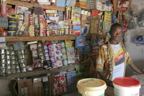 Tanji Village.  Young  male owner of a grocery shop standing behind wooden counter in front of shelves with display of various products.TanjehTanjihAfricanmerchandisestoretradesmall business...