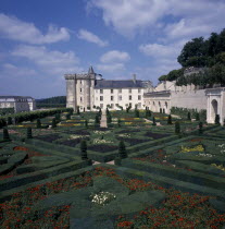 View across gardens to chateau with blue and cloudy sky.
