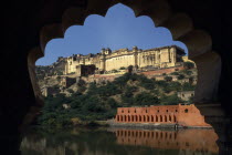 Amber Palace Fort near Jaipur situated on hillside above lake framed by scalloped edge of silhouetted window.