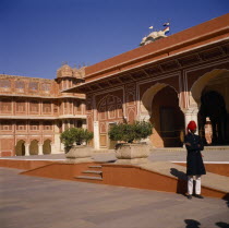 Palace exterior with man wearing red turban standing in grounds