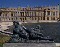 Versailles. Part view of palace with bronze reclined statue of woman with child next to pond