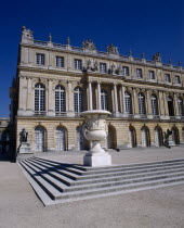 Versailles. Part view of palace with steps and white urn  arched windows and blue sky