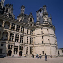 Chambord Chateau. Tourists on gravelled entrance near round tower