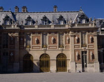 Versailles. Part of palace with statues on walls  arches  balustraded roof and gravel in foreground