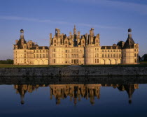 Chateau Chambord in golden light  reflected in moat in foreground
