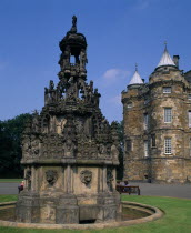 Holyrood Palace  part view of western exterior with ornate carved  stone fountain in the foreground.