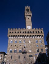 Palazzo Vecchio.  Facade of medieval palace completed in 1322 and used as the town hall.  Crenellated roof and clock tower with statues outside entrance including copy of Michelangelos David.