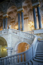 The Winter Palace of the Hermitage Museum.  Detail of the Jordan Staircase and opulent white and gold interior decoration and marble columns.  Visitors on balcony.